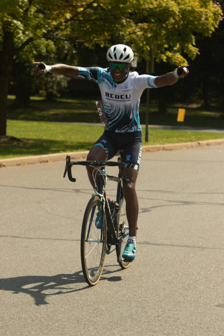 A man riding a bike on the street with his arms in the air.